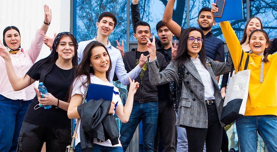 Students in front of Tashkent campus building, smiling