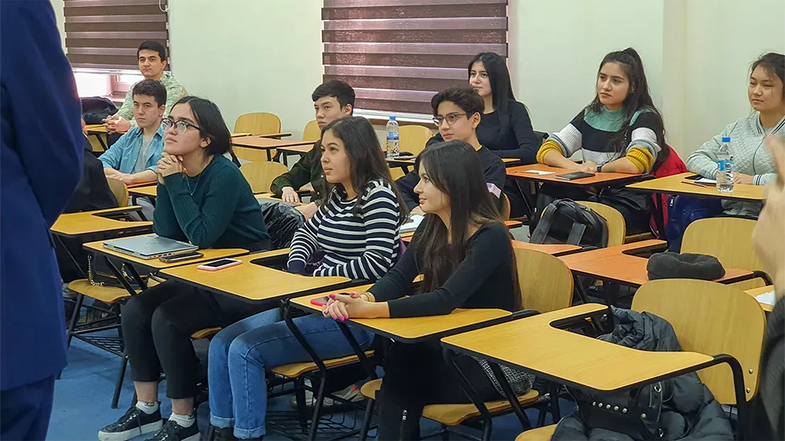 Classroom full of students listening intently to professor in front. 