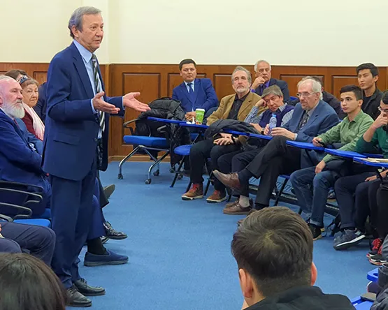 Speaker stands and gives talk in large classroom group of seated attendees.