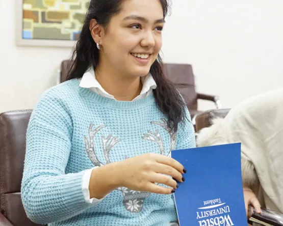 student flips through Webster Tashkent brochure