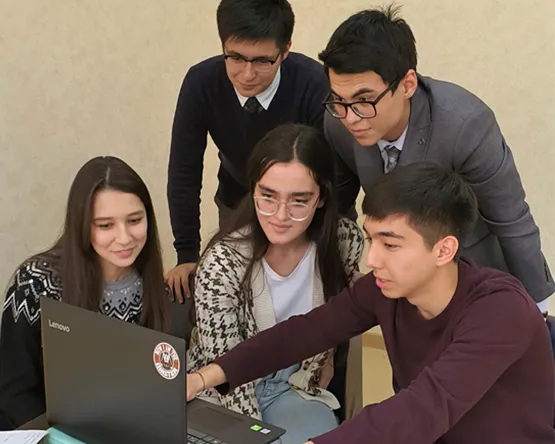 group of students huddled around to look at laptop
